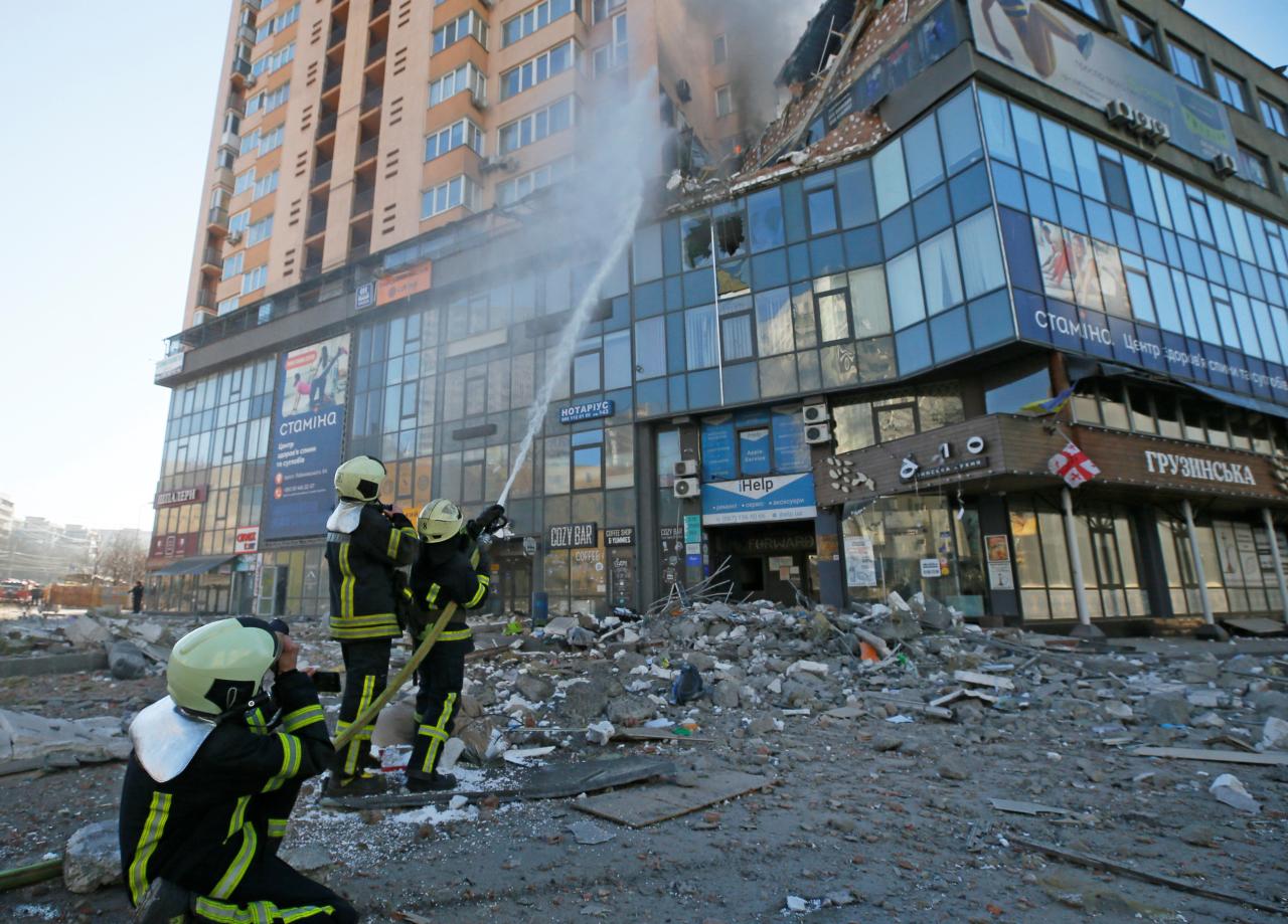 Bomberos combatiendo un incendio en un rascacielos con un impacto de bala