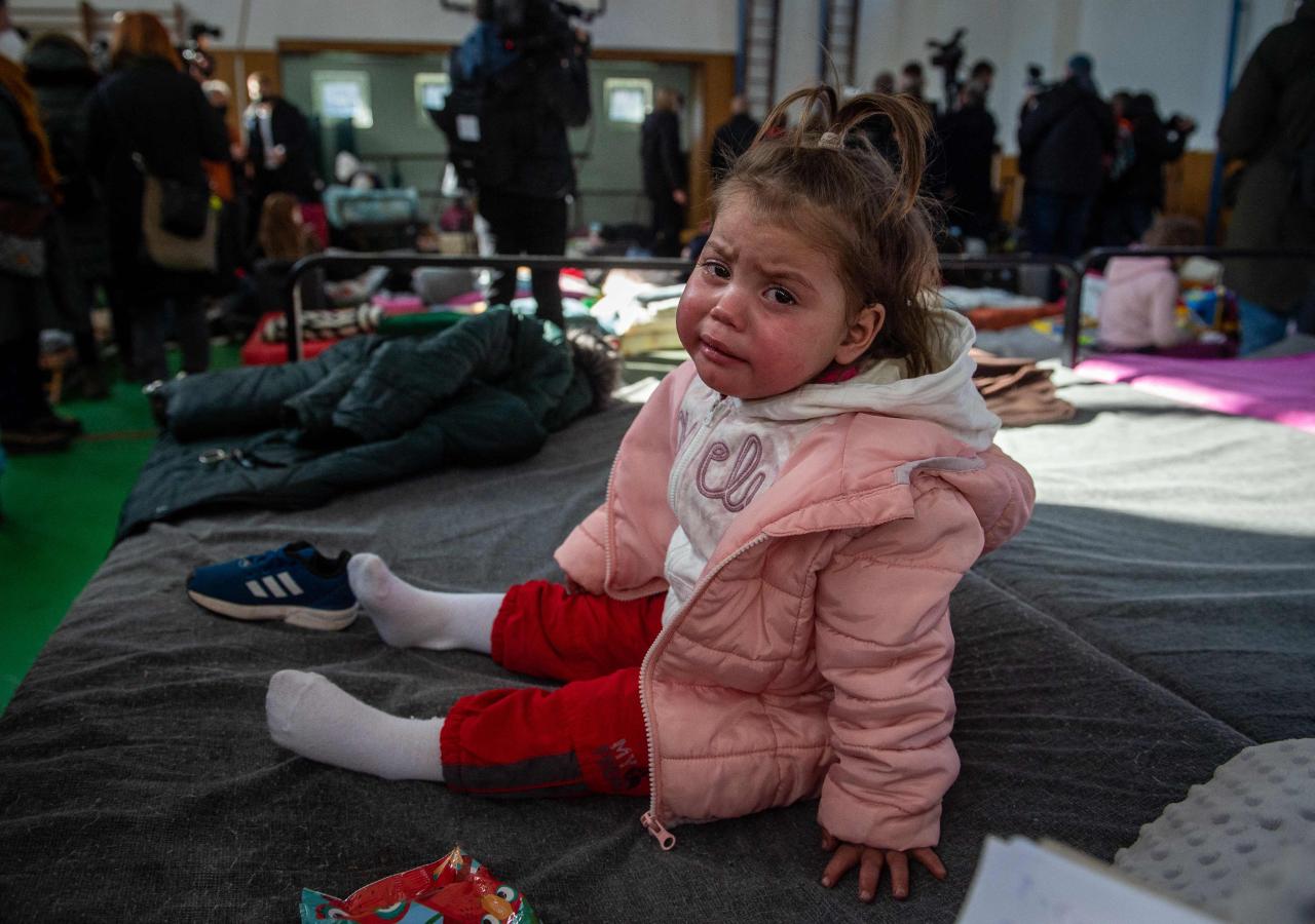 Una niña llora mientras está sentada en una cama plegable en un refugio temporal para refugiados ucranianos en el cruce fronterizo de Ubli, en el este de Eslovaquia.