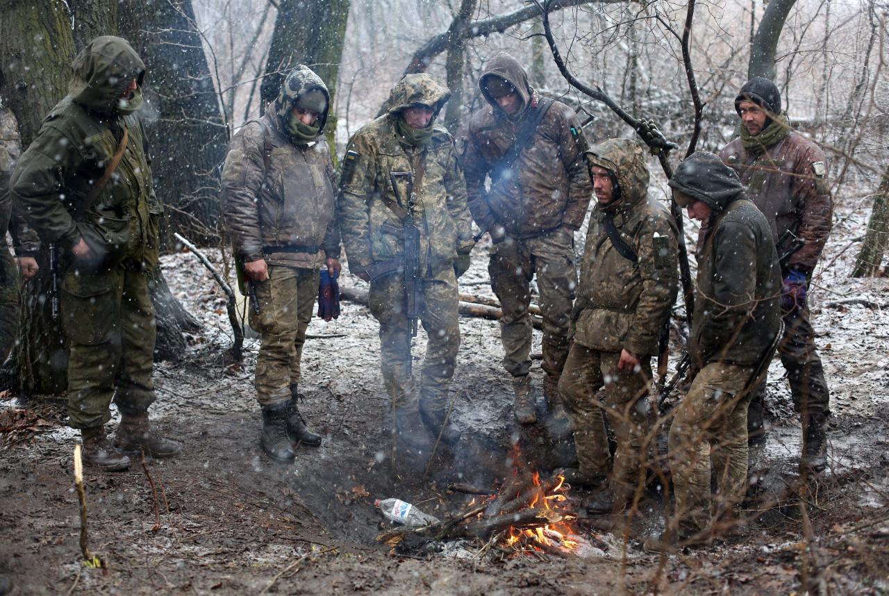 Los soldados ucranianos se calientan junto al fuego.