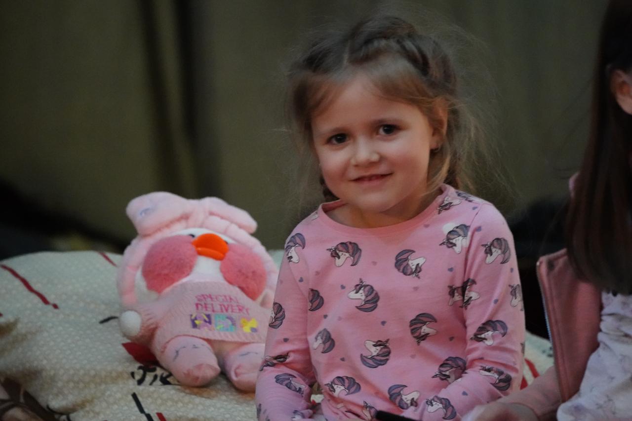 La hermana menor de Arina, Katia, de 4 años, sonríe junto a su pato de juguete Milka después de escapar del bombardeo en Kiev.