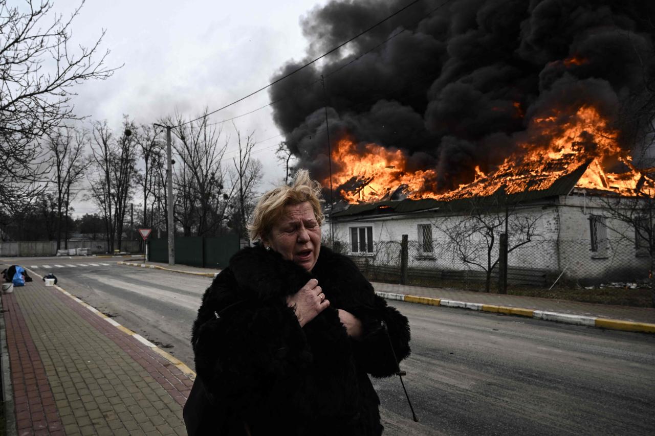 La mujer reacciona frente a una casa en llamas después de que le dispararan en la ciudad de Irpin.