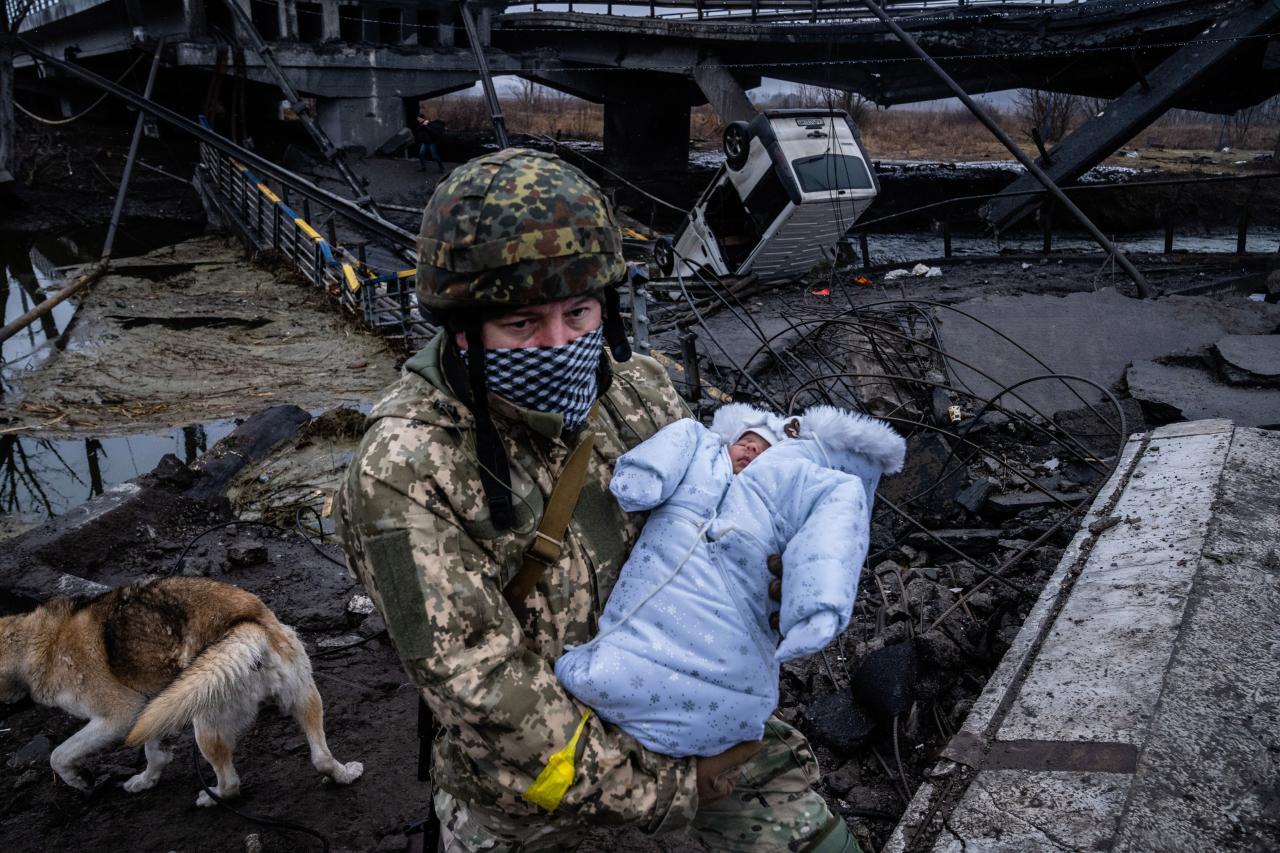 Un soldado ucraniano lleva a un niño a través de un puente en ruinas en las afueras de Kiev.