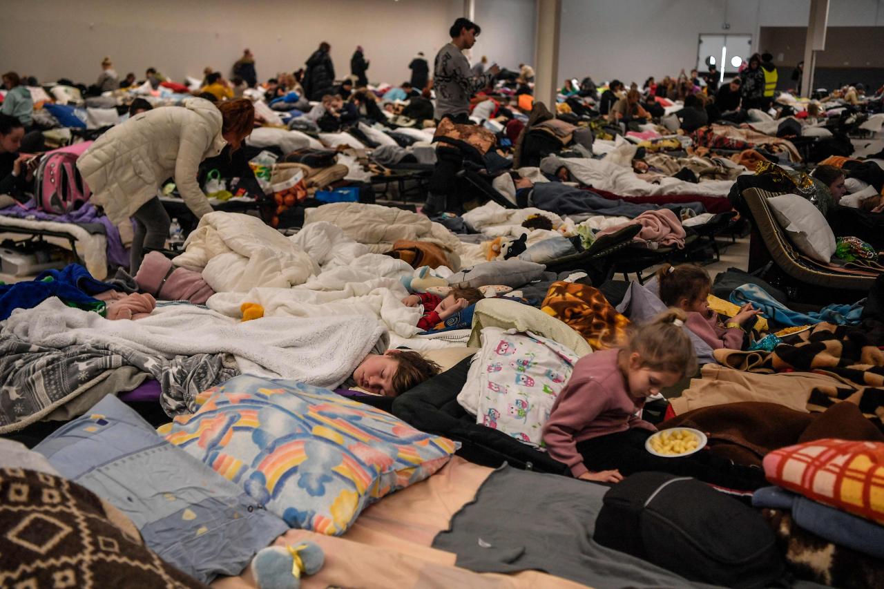 Las personas descansan en un refugio temporal para refugiados ucranianos, ubicado en la frontera entre Polonia y Ucrania en un antiguo centro comercial en Przemyśl.