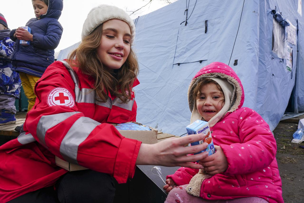 La voluntaria de la Cruz Roja Anna Bilas, de 25 años, diseñadora de ropa antes de la crisis, distribuye leche a Elisa, una niña de cuatro años de Kharkiv.