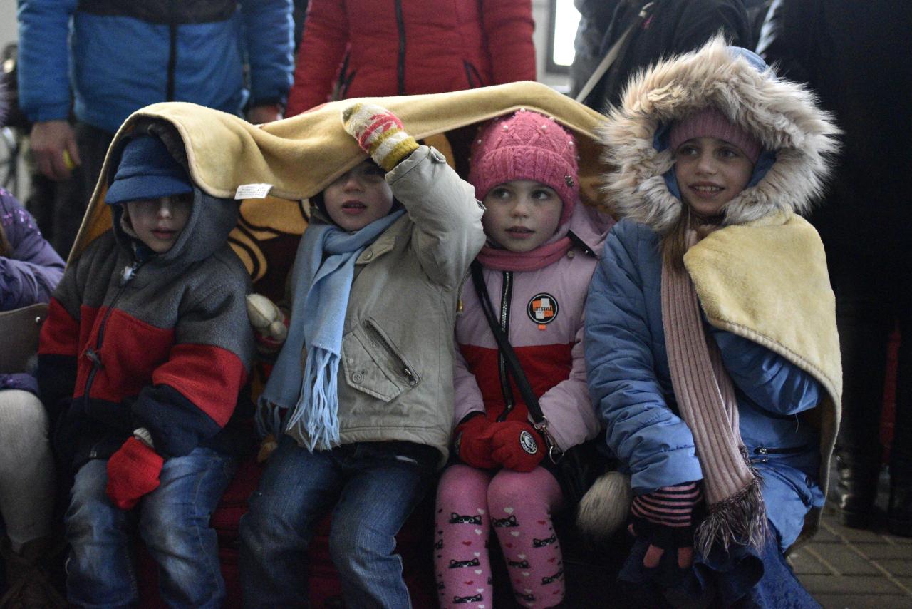 Cuatro niños comparten una manta para mantenerse calientes en la estación de tren de Lviv