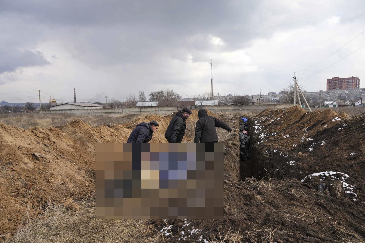 Los cuerpos se colocan en una fosa común recién excavada en Mariupol.