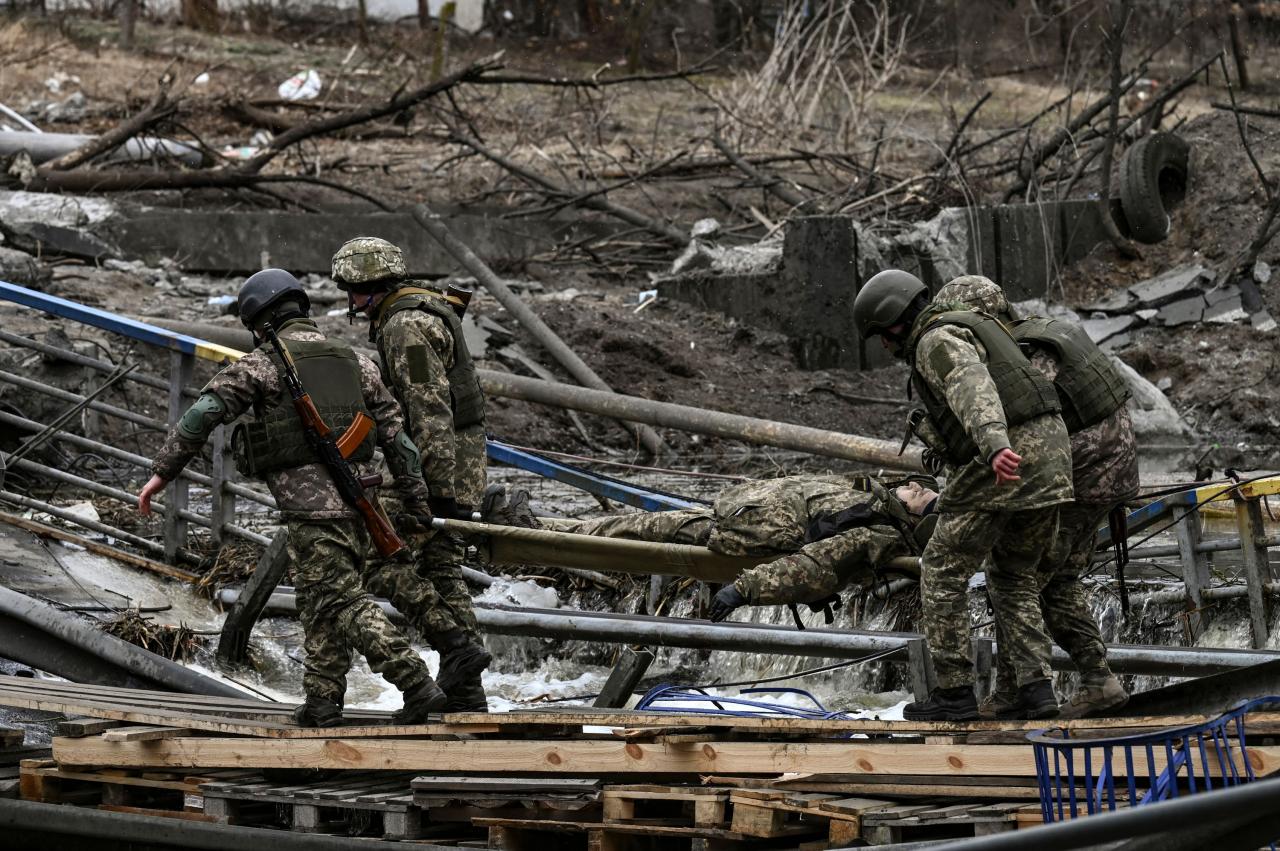 Cuatro soldados en Irpin llevan el cuerpo de un camarada en una camilla