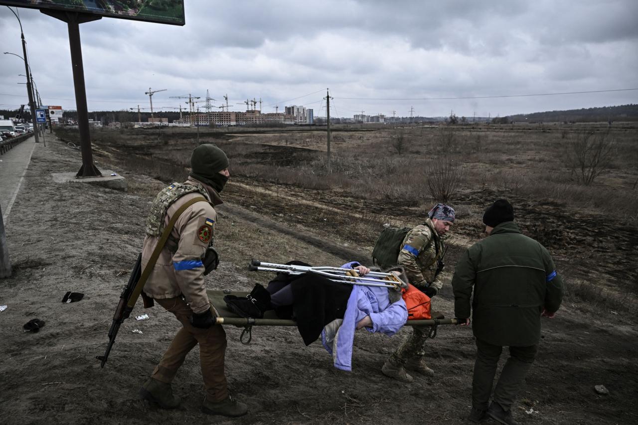 Soldados ucranianos evacuan a una anciana en camilla de la ciudad de Irpin