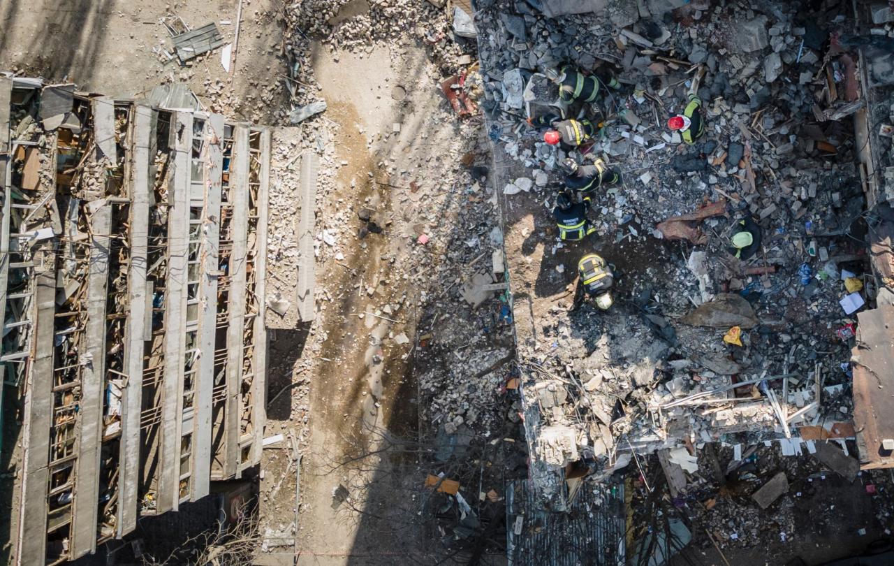 Vista aérea muestra a los bomberos trabajando en los escombros de un edificio de apartamentos que fue alcanzado por los escombros de un cohete derribado en Kiev.