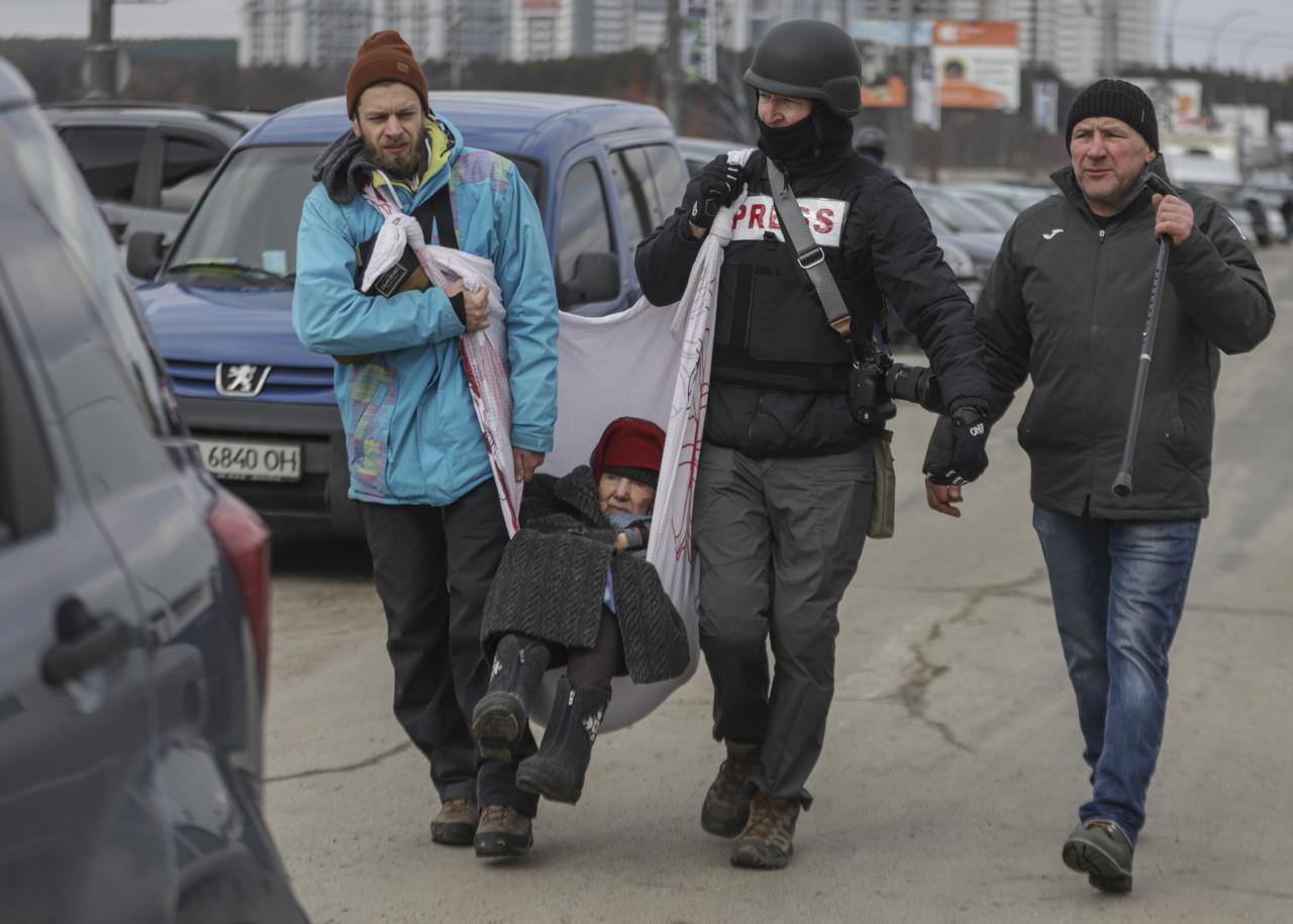Residentes y periodistas ayudan a una anciana a escapar de la ciudad fronteriza de Irpin, cerca de Kiev.
