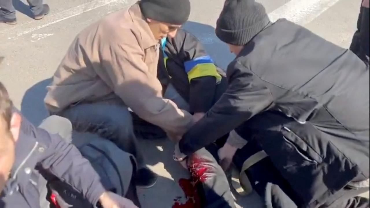 Un civil que protesta yace en el suelo, sangrando por una herida en la pierna.