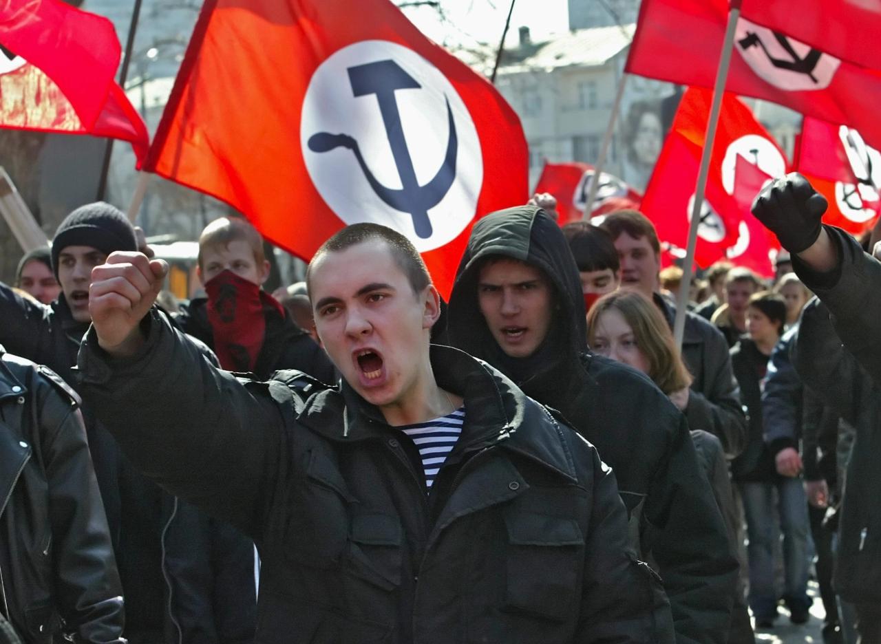 Miembros del Partido Nacional Bolchevique ondean banderas con una hoz y un martillo