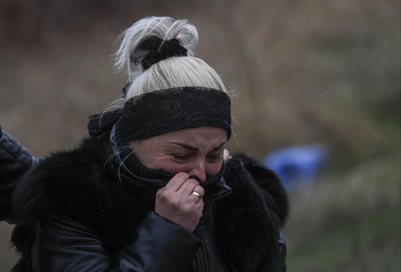 Una mujer llora al reconocer los cuerpos de sus familiares encontrados en una fosa común en Bucha