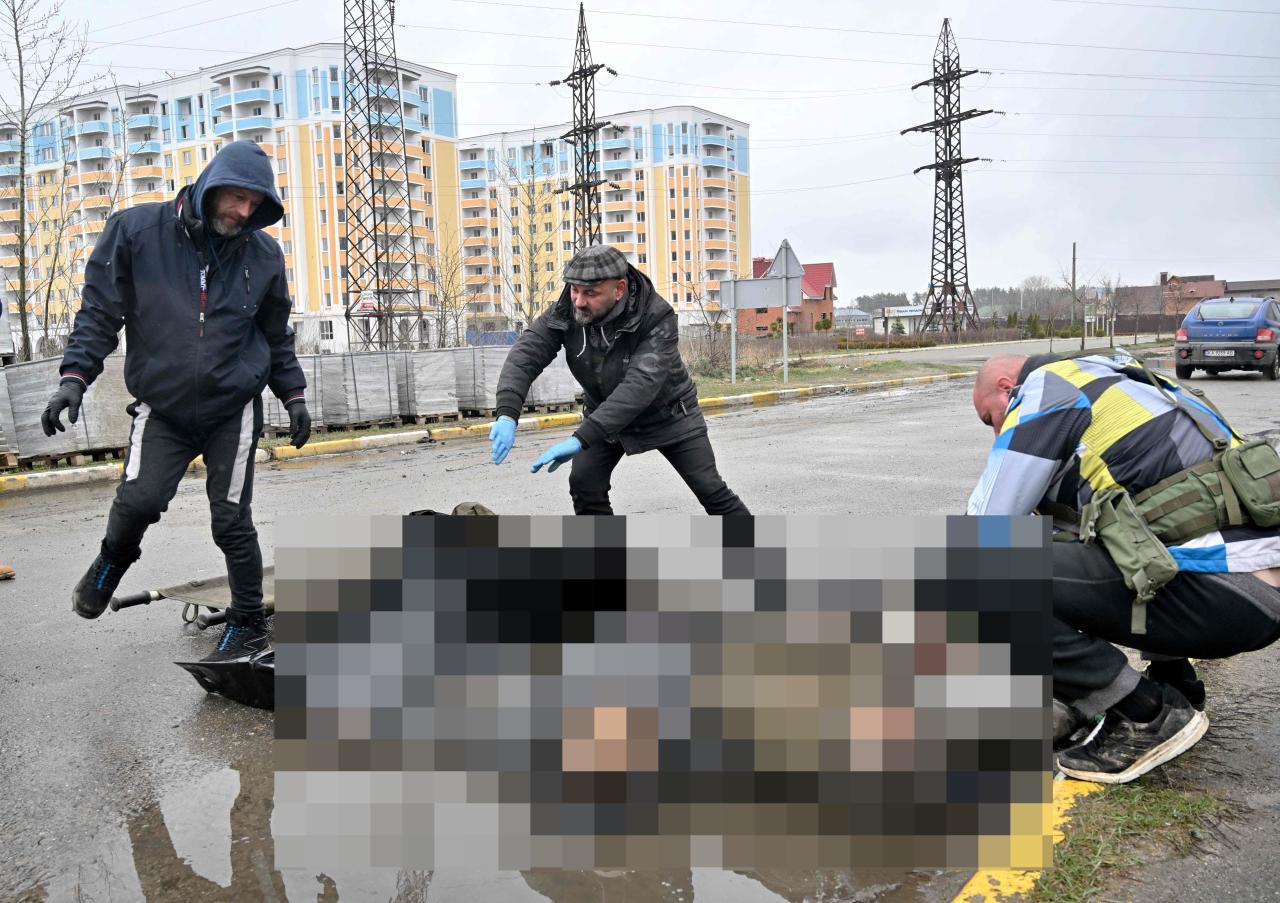 Trabajadores municipales recogen los cuerpos de dos hombres muertos durante el bombardeo de la ciudad de Buczań por parte del ejército ruso