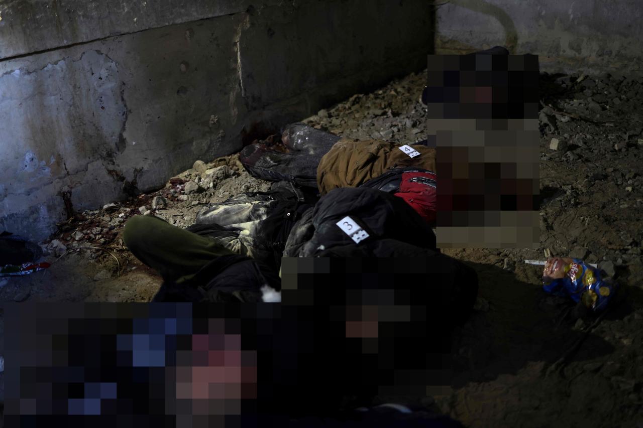 Cadáveres gravemente mutilados de personas que parecen ser hombres esparcidos por el suelo mientras los rescatistas transportaban víctimas inocentes en bolsas para cadáveres.