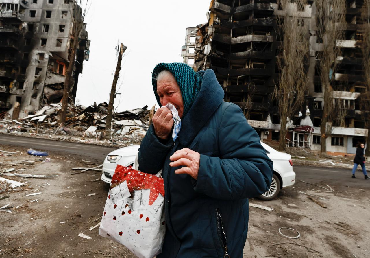 Nina, de 74 años, residente de Borodiankava, rompe a llorar al pasar frente a los edificios destruidos por los bombardeos rusos.