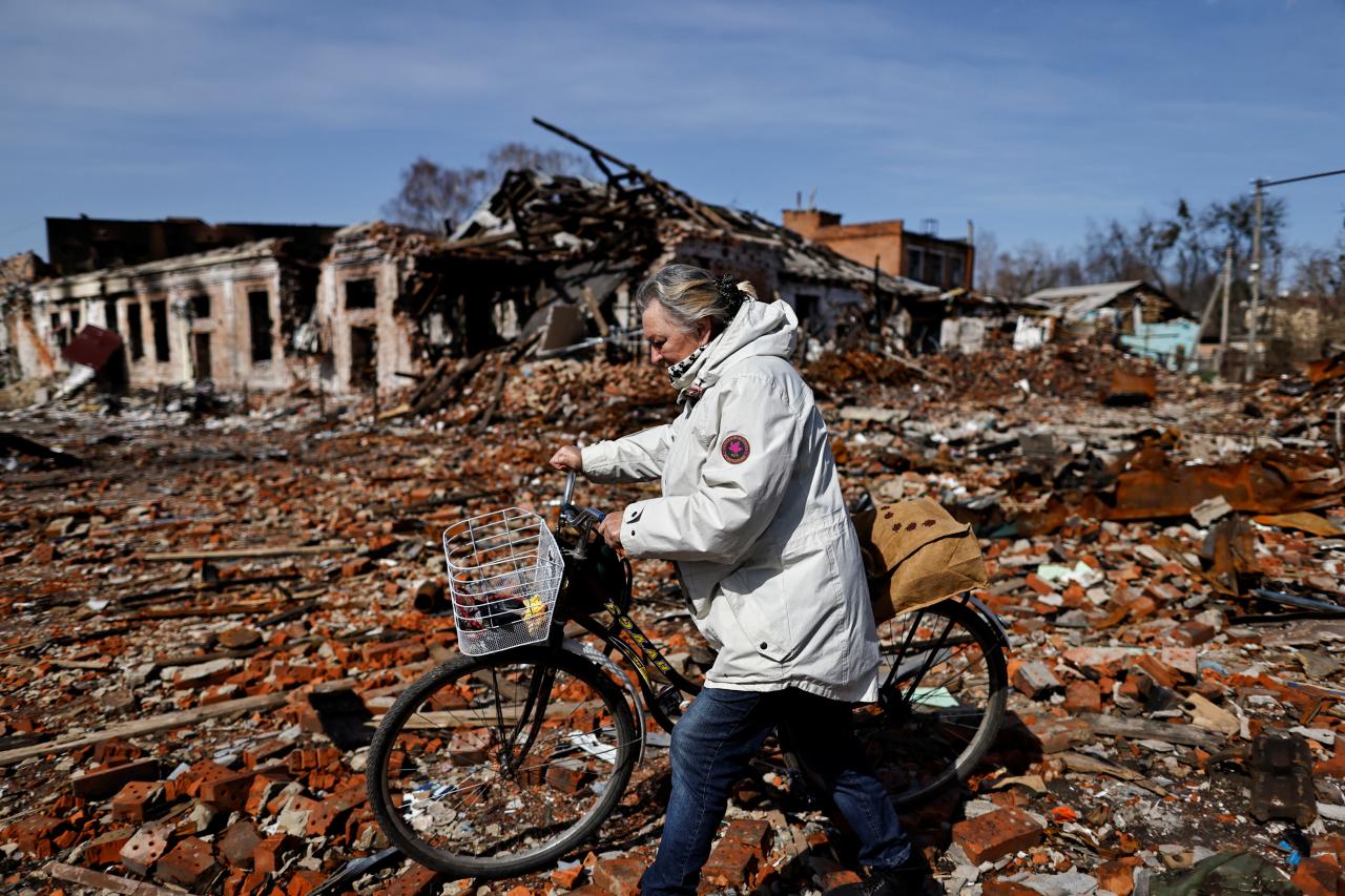 Una mujer empuja su bicicleta a través de las ruinas de Trostianets, región de Sumy, Ucrania