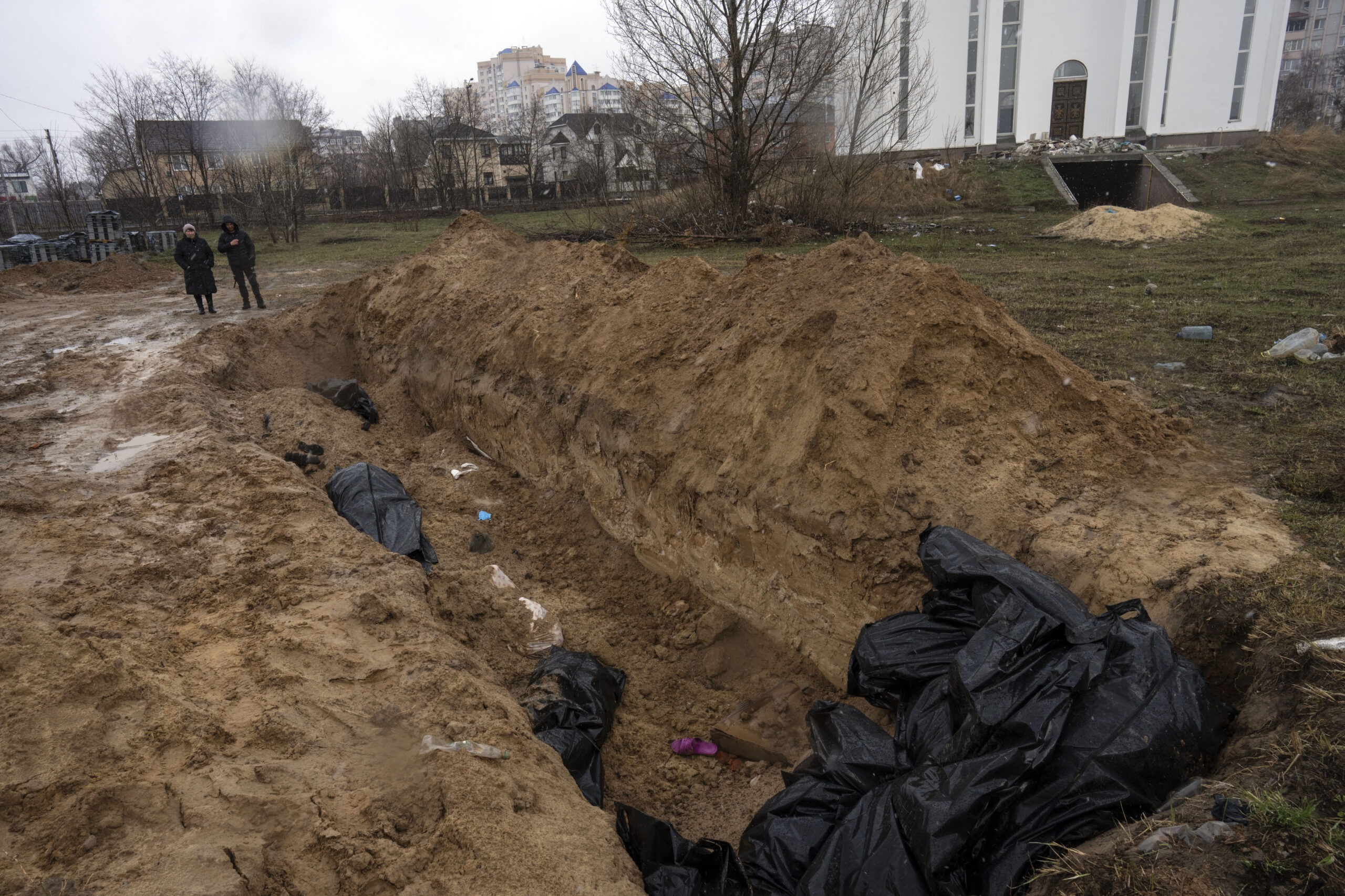 Los vecinos se reúnen junto a una fosa común en Bucza, en las afueras de Kiev, Ucrania.