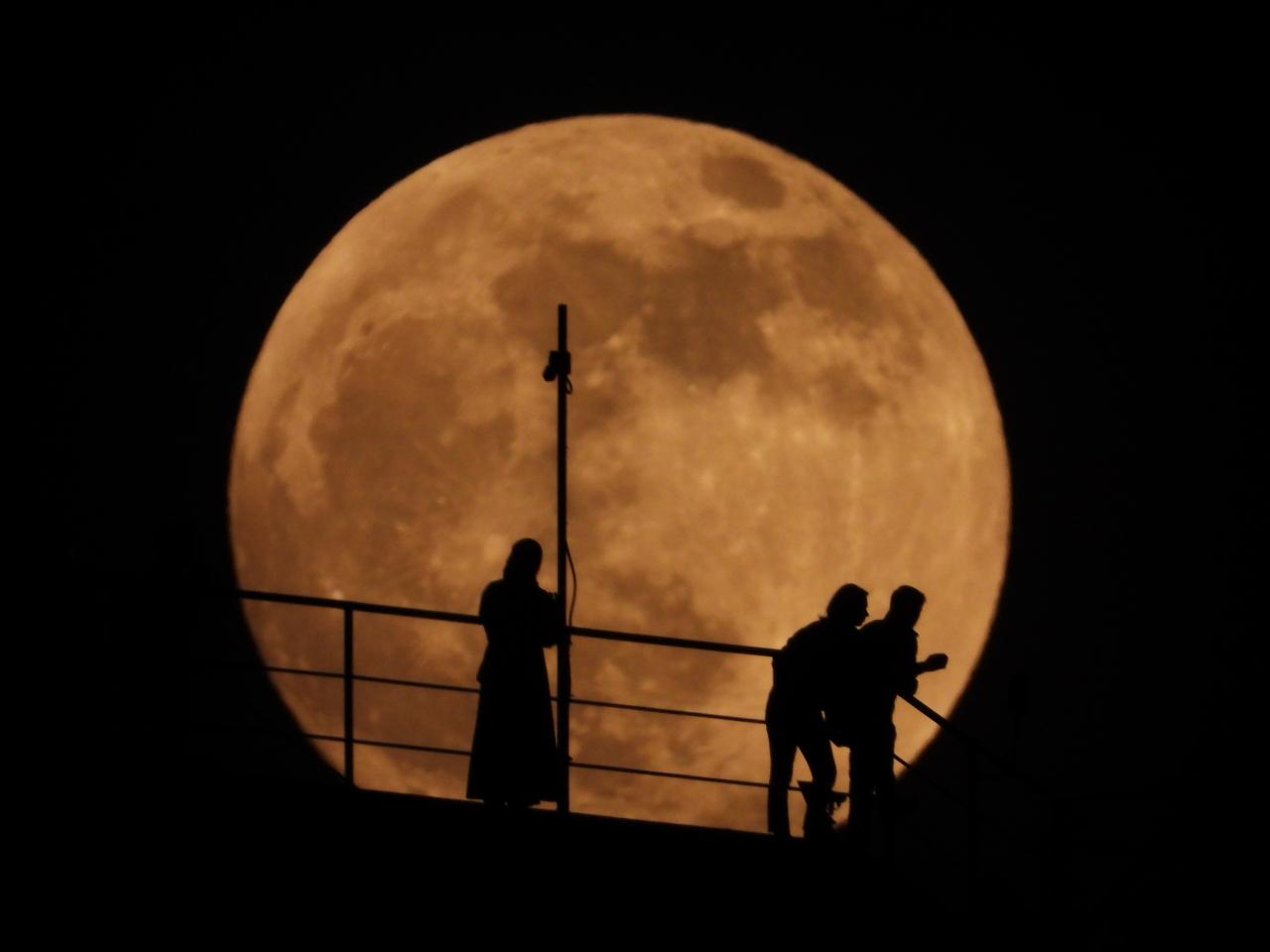La gente dibuja mientras la luna llena se eleva sobre el cielo en Grozny, Rusia