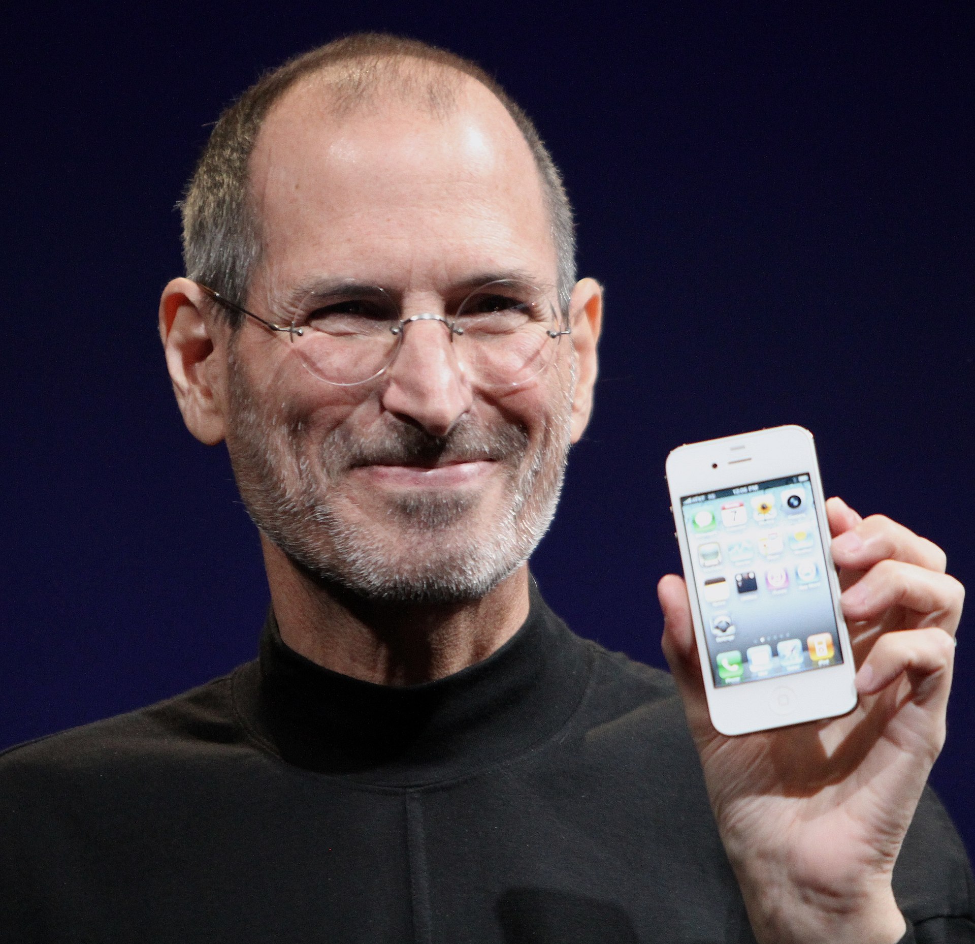 Steve Jobs con sus icónicos anteojos, sosteniendo el iPhone 4